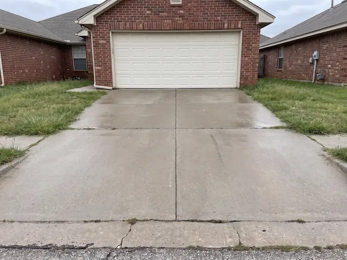 The same driveway after pressure washing, the concrete an even light grey